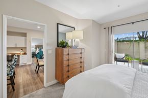 Dublin apartment for rent - A bedroom with a large bed and a dresser with a mirror above it at Park Sierra at Iron Horse Trail in Dublin.