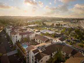 Laguna Hills apartment for rent - A sunny day in a residential area with apartment buildings and a pool.
