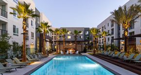 Cypress apartment for rent - a swimming pool in front of a building with palm trees