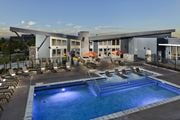 Highlands Ranch apartment for rent - A large outdoor swimming pool with lounge chairs and umbrellas in front of a modern building.