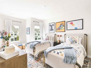 Hoschton apartment for rent - A bedroom with two beds, one with a blue blanket, and a wooden dresser with a vase of flowers on top.