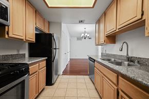 Los Angeles apartment for rent - a kitchen with wooden cabinets and a sink and a black refrigerator