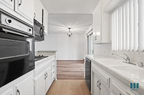 Los Angeles apartment for rent - A kitchen with white cabinets and a black stove top oven.