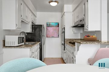 Los Angeles apartment for rent - A kitchen with white cabinets and a pink chair.
