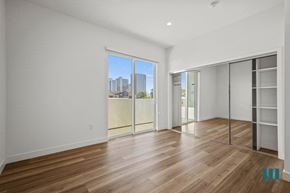 Los Angeles apartment for rent - A spacious room with wooden flooring and a view of the city through a large window.