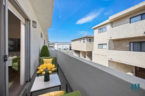Los Angeles apartment for rent - A balcony with a table and chairs overlooks a row of buildings.