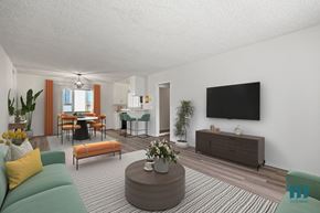 Los Angeles apartment for rent - A living room with a green sofa, a wooden coffee table, and a flat-screen TV mounted on the wall.