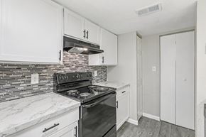 Orlando apartment for rent - A kitchen with a black stove top oven and white cabinets.