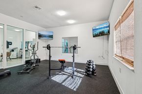 New Smyrna Beach apartment for rent - A gym room with a variety of equipment including a treadmill, exercise bike, and weight stacks.
