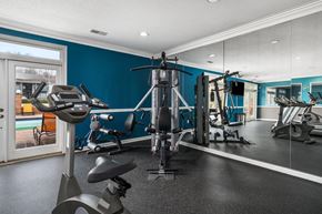 Birmingham apartment for rent - a gym with weights and cardio equipment in a home with blue walls and a window at Ascot Place Apartments, Birmingham Alabama