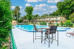 Daytona Beach apartment for rent - A poolside table with chairs is set up by a swimming pool.