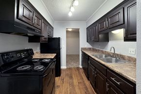 Birmingham apartment for rent - a kitchen with black appliances and dark wood cabinets at Ascot Place Apartments, Birmingham, AL 35235