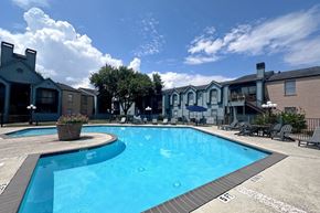 Houston apartment for rent - A large swimming pool surrounded by lounge chairs and umbrellas.