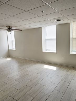 Logansport apartment for rent - A room with a ceiling fan and light, tile flooring, and two windows.