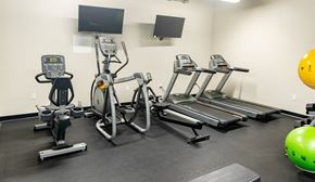 South Bend apartment for rent - a gym with four ellipticals and a tv on the wall