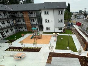 Marysville apartment for rent - A playground area with a slide and a green umbrella is surrounded by apartment buildings.