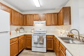 Woodbridge apartment for rent - A kitchen with wooden cabinets and a white refrigerator.