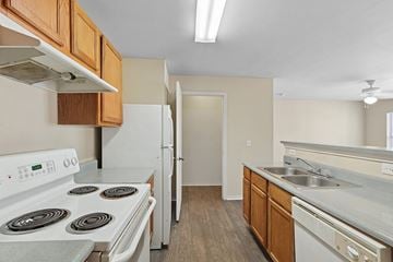 Fort Worth apartment for rent - A kitchen with a white stove top oven and a white refrigerator.