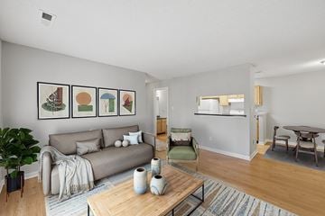 Durham apartment for rent - A living room with a grey couch, a green chair, a wooden coffee table and a painting on the wall.