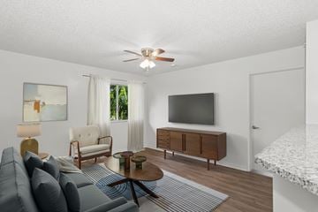 Miami apartment for rent - A living room with a grey sofa, a wooden coffee table, a flat screen TV, and a painting on the wall.