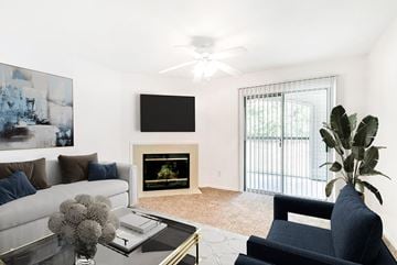 Nashville apartment for rent - A living room with a fireplace, a couch, a chair, a coffee table, a plant, and a painting on the wall.
