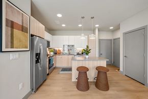 Broomfield apartment for rent - A kitchen with a refrigerator, stove, and bar stools.