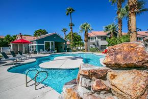 Las Vegas apartment for rent - a swimming pool with a stone wall and chairs around it