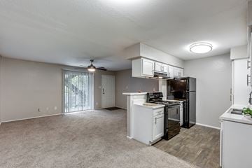 Austin apartment for rent - A white kitchen with a black refrigerator and a fan on the ceiling.
