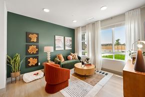 Broomfield apartment for rent - A living room with a green couch, a brown armchair, a wooden coffee table, and a large window with a view of the outdoors.
