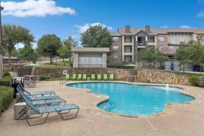 Weatherford apartment for rent - A swimming pool surrounded by a stone wall and lounge chairs.