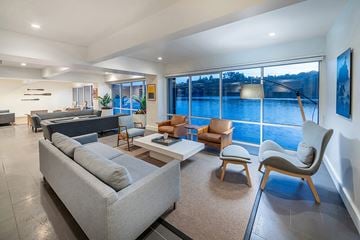 Tiburon apartment for rent - A modern living room with a grey sofa and a large window overlooking a body of water.