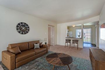 Austin apartment for rent - A living room with a brown couch and a clock on the wall.