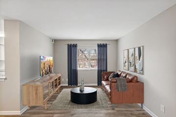 Glen Burnie apartment for rent - A living room with a brown leather couch and a wooden cabinet.
