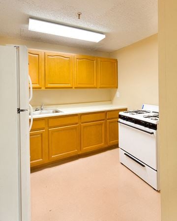 Bronx apartment for rent - A kitchen with wooden cabinets and a white stove.