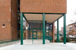 Bronx apartment for rent - A red brick building with a green trimmed entrance.