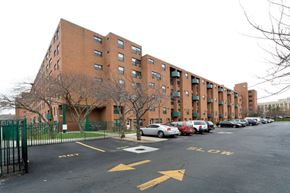Bronx apartment for rent - A parking lot in front of a brick apartment building.