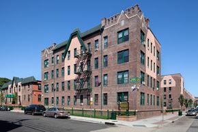 Hempstead apartment for rent - A red brick building with a green roof and a fire escape.