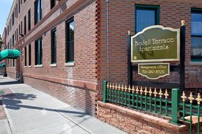 Hempstead apartment for rent - Bedell Terrace Apartments is a brick building with a green fence.