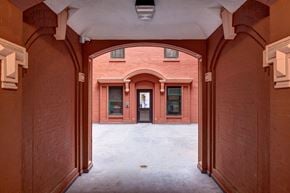 Bronx apartment for rent - A brick archway leads to a building with a black door.