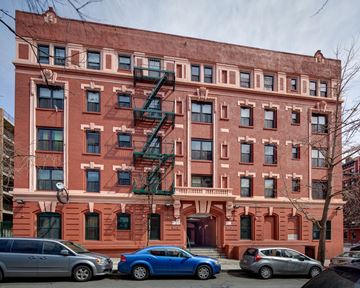 Bronx apartment for rent - A red brick building with a green fire escape.