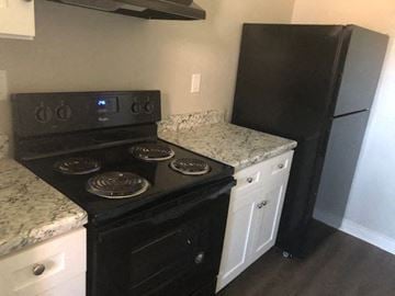 Hartford apartment for rent - A black stove top oven with four burners and a digital display is in a kitchen with a black refrigerator and a marble counter top.