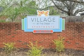 Clarkston apartment for rent - A sign for Village at the Creek Apartments is displayed on a brick wall.