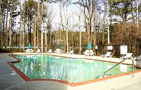 Clarkston apartment for rent - A pool surrounded by trees and chairs at Clarkston Station Apartments, Clarkston, Georgia