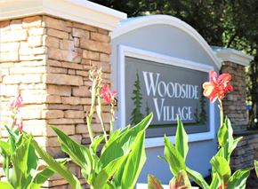 Clarkston apartment for rent - A sign that says Woodside Village with flowers in front at Woodside Village Apartments, Clarkston, 30021