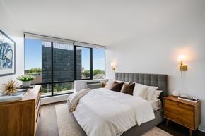 Fort Lee apartment for rent - A bedroom with a large bed and a view of a city skyline.