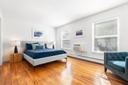 Roseland triplex for rent - A bedroom with hardwood-style flooring, two large windows, and a portable cooling/heating unit on the wall.