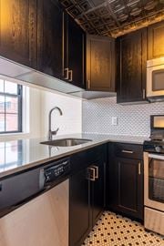 Hoboken apartment for rent - A kitchen with black cabinets and a white tiled backsplash.