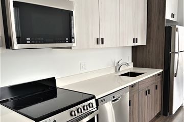 Milford apartment for rent - A modern kitchen with a black stove top oven and white cabinets.