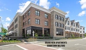 Milford apartment for rent - A large brick building with a sign that says "Brand New Apartments Downtown Milford".