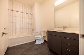 Detroit apartment for rent - A white toilet sits in a bathroom with a white tiled shower.